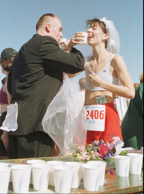 Kevin and Andrea Gust toast to a cold cup of water to celebrate their finish in the 1997 Capitol 10,000 race and their marriage the day before. They ran the entire race, he in his Tuxedo, and she wearing running attire with her veil and wedding flowers. "Tomorrow we start the honeymoon." [Ralph Barrera/American-Statesman]